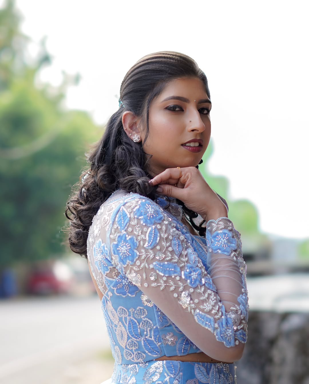 Soft curls and party makeup in a blue embroidered outfit